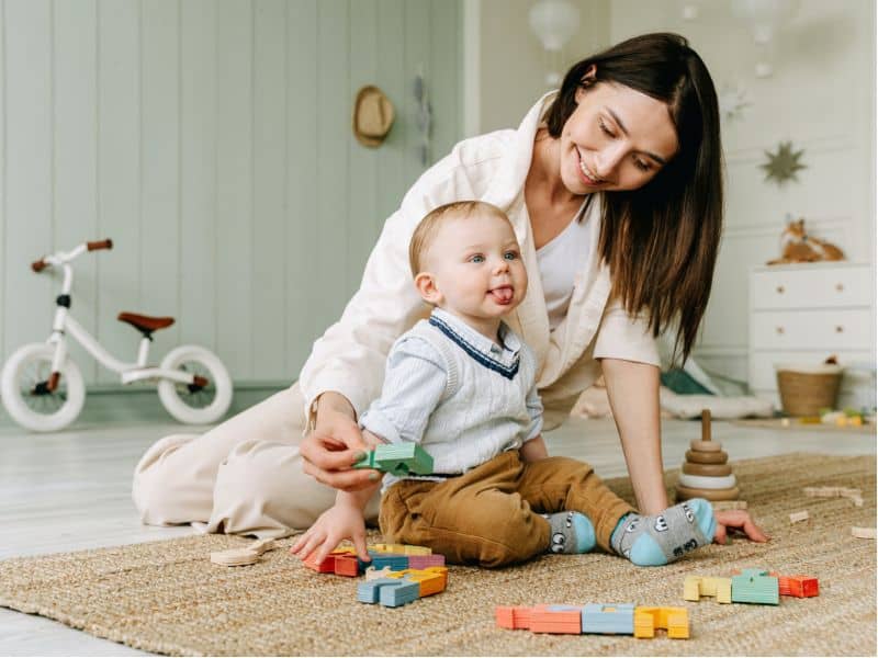 baby boy sitting on floor with sensory toys 1