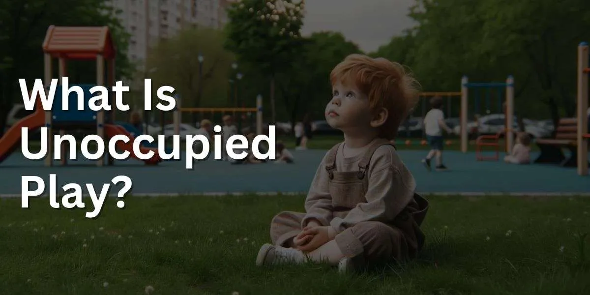 Photo of a park scene where a toddler with fair skin and red hair is seated on the grass, gazing up at the sky. The child is surrounded by playground equipment and other kids playing, but the child remains in a moment of contemplation, representing the unoccupied play stage.