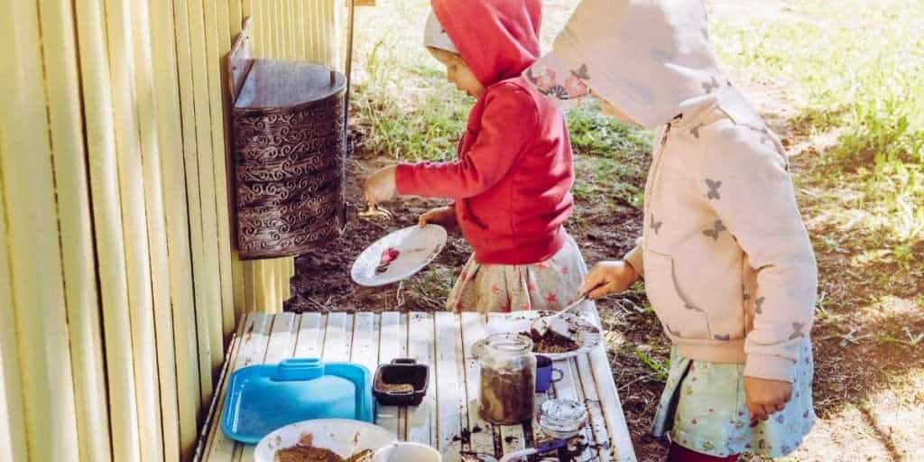 A mud kitchen with kids playing and having fun with mud pies, nature-inspired recipes and potion experiments