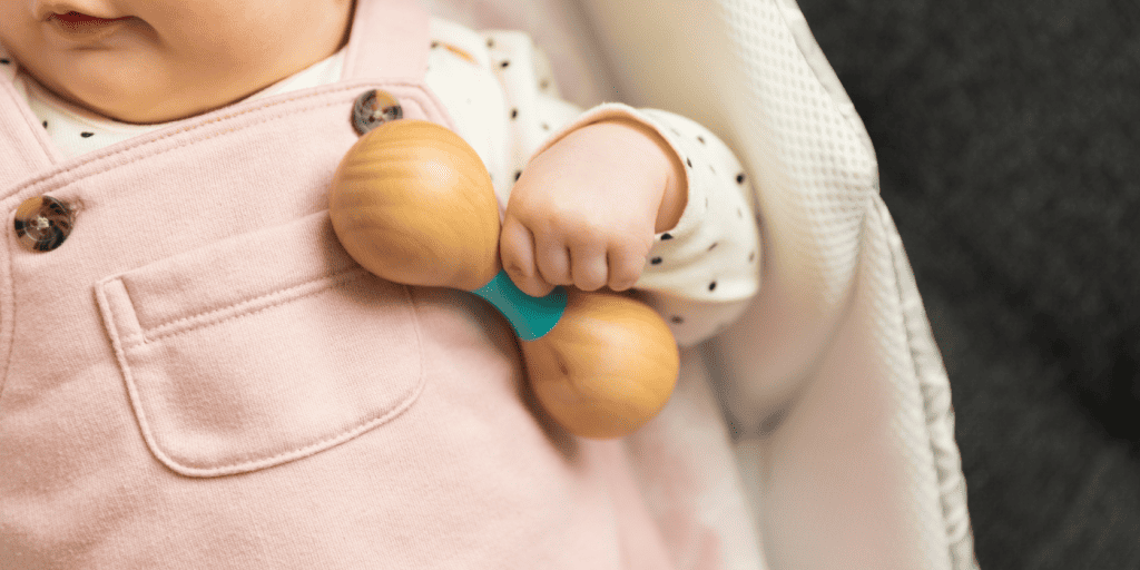 When do babies 2024 start holding rattles